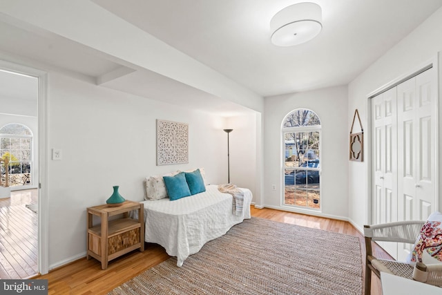 bedroom with light wood-type flooring, a closet, and baseboards