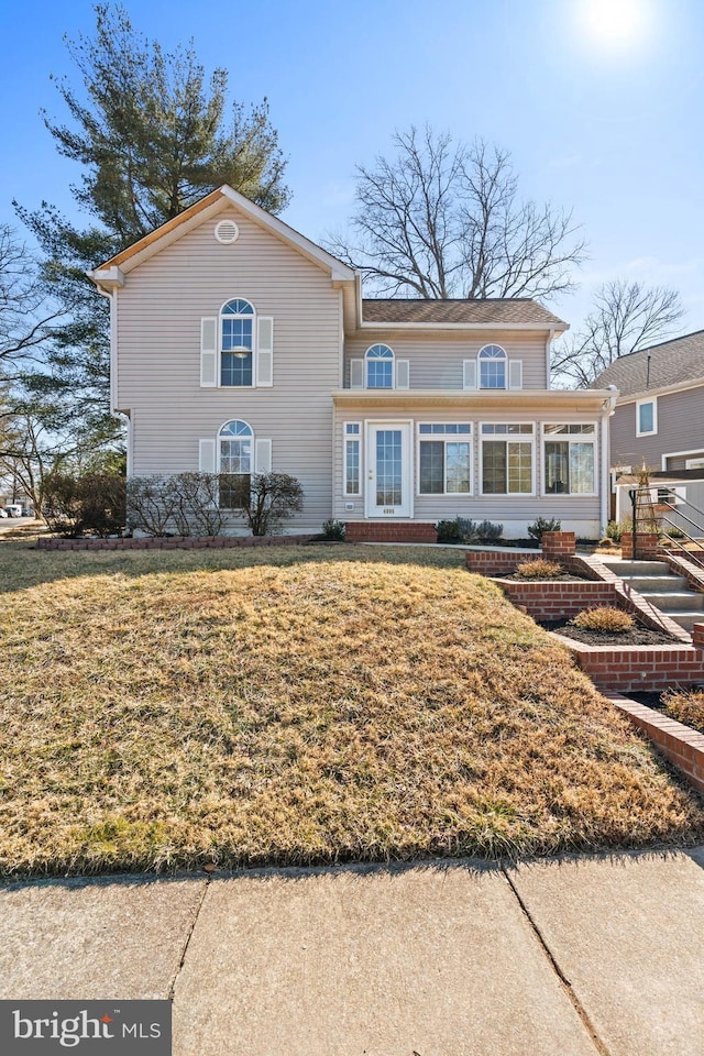 view of front of property with a sunroom and a front lawn