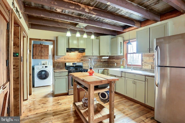 kitchen featuring stainless steel appliances, washer / clothes dryer, green cabinets, a sink, and under cabinet range hood