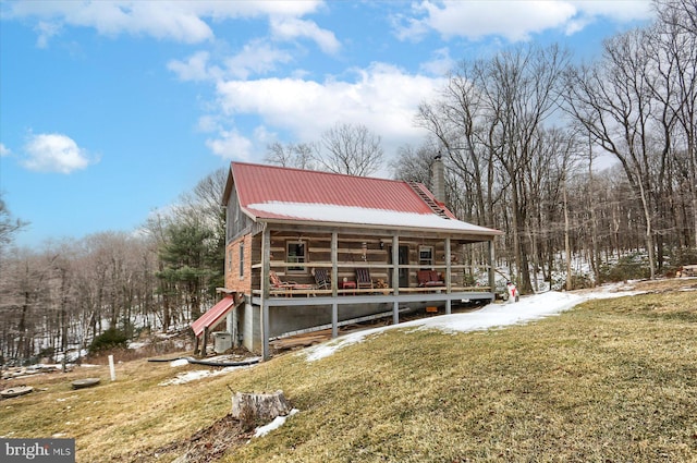 exterior space with a chimney, metal roof, and a yard