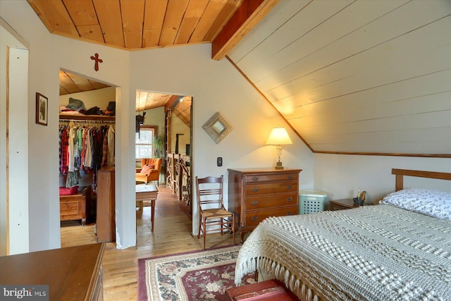 bedroom with lofted ceiling with beams, wood ceiling, a walk in closet, light wood-type flooring, and a closet