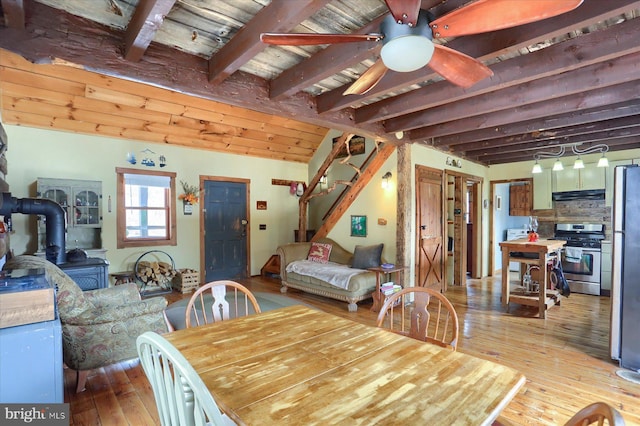 dining space with stairs, ceiling fan, lofted ceiling with beams, and hardwood / wood-style flooring