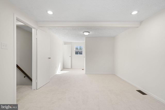 interior space with baseboards, visible vents, a textured ceiling, and light colored carpet