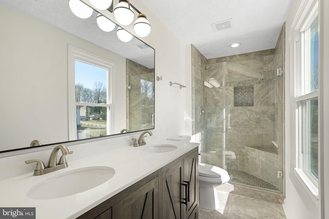 full bath featuring toilet, a sink, visible vents, and a shower stall