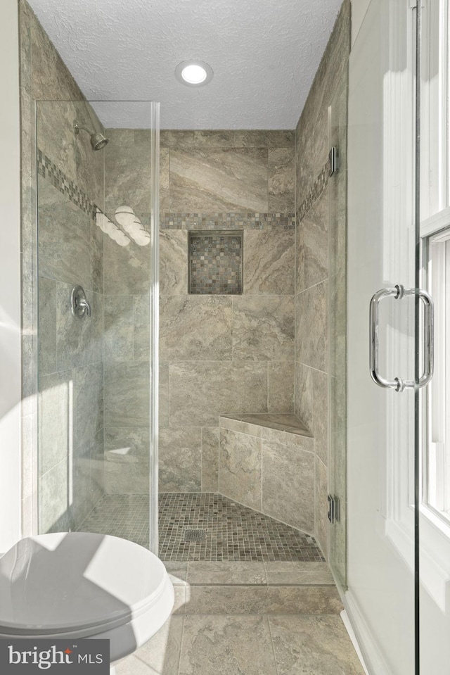 bathroom featuring a textured ceiling and a stall shower