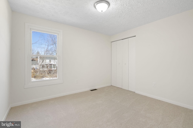 unfurnished bedroom featuring light carpet, baseboards, visible vents, and a closet