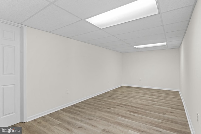 unfurnished room with light wood finished floors, baseboards, and a drop ceiling