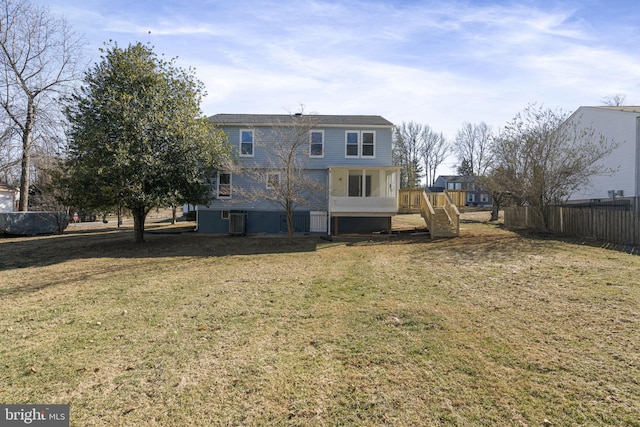 rear view of property with a yard, stairway, and fence