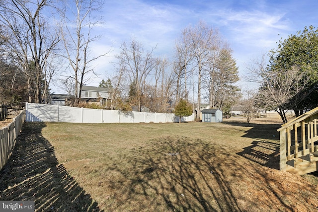 view of yard with an outbuilding, a fenced backyard, and a shed