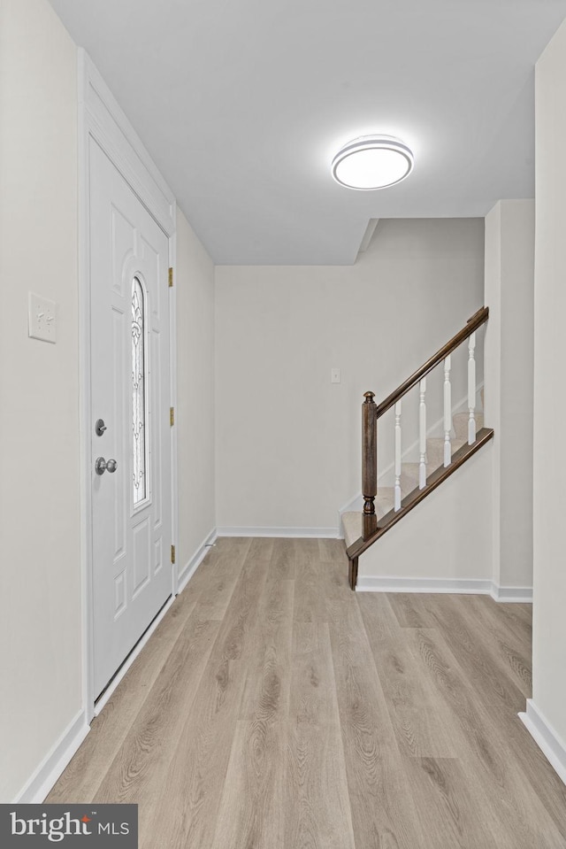 foyer featuring stairs, light wood finished floors, and baseboards