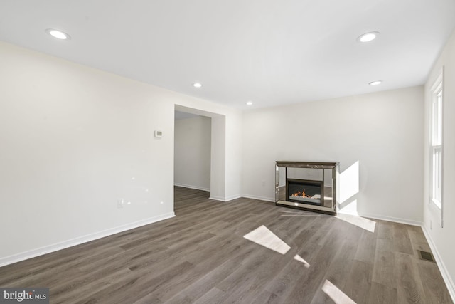 unfurnished living room featuring recessed lighting, visible vents, dark wood finished floors, and a glass covered fireplace