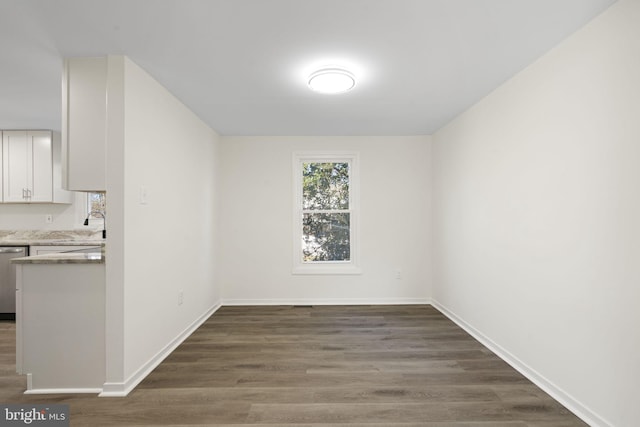 unfurnished dining area with dark wood-style floors and baseboards