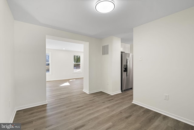 unfurnished room with wood finished floors, visible vents, and baseboards