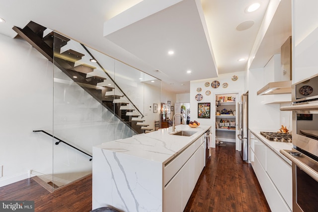 kitchen featuring modern cabinets, a sink, a kitchen island with sink, and white cabinetry