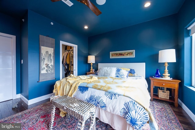 bedroom featuring dark wood-type flooring, baseboards, a walk in closet, and a closet