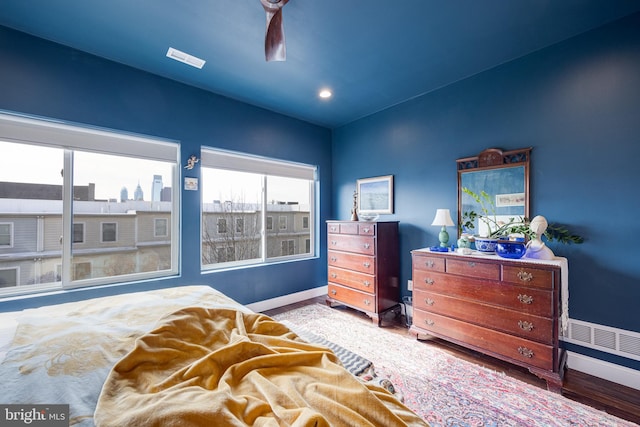 bedroom with ceiling fan, baseboards, a city view, and wood finished floors