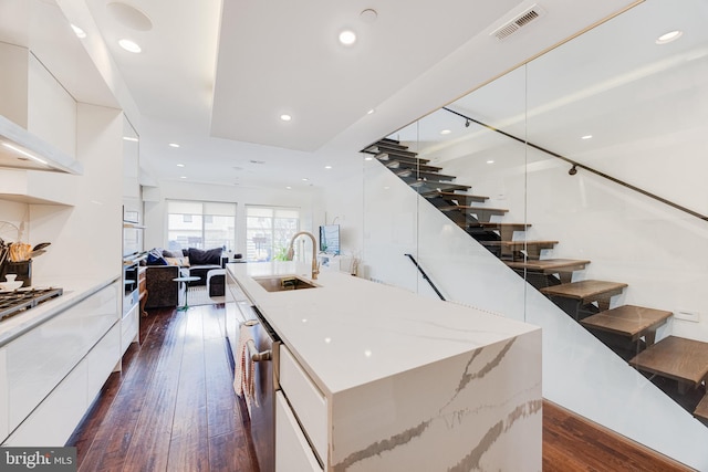 kitchen featuring a spacious island, modern cabinets, a breakfast bar area, and a sink