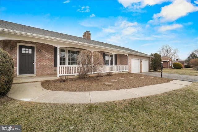 ranch-style house with covered porch, brick siding, a chimney, and an attached garage