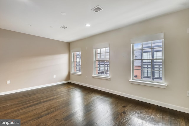 empty room featuring dark wood-type flooring, recessed lighting, visible vents, and baseboards