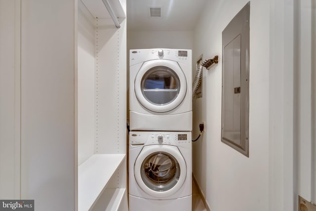 laundry room featuring stacked washer / drying machine, electric panel, and visible vents