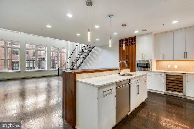 kitchen featuring wine cooler, pendant lighting, stainless steel appliances, dark wood-type flooring, and a sink