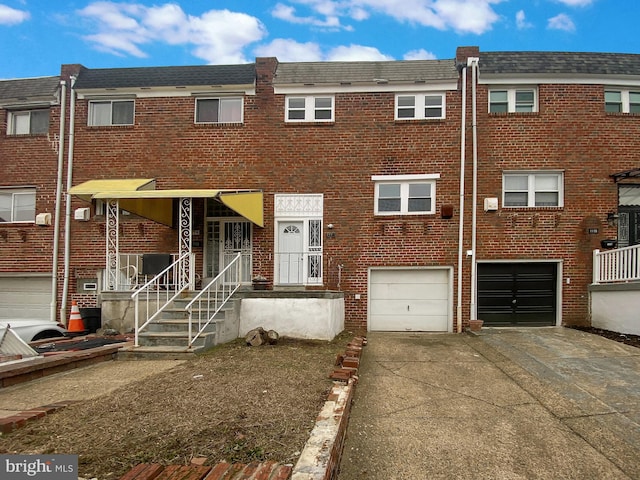 view of property with a garage, brick siding, and driveway