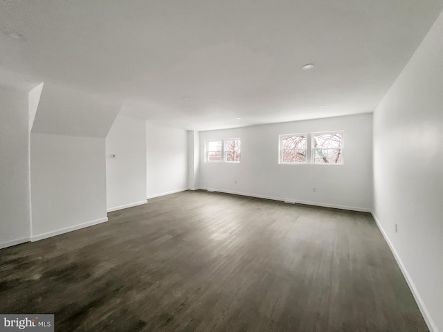 additional living space with dark wood-style flooring and baseboards