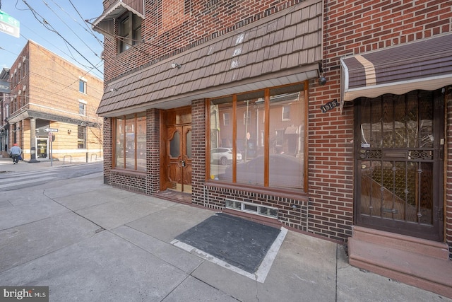 doorway to property featuring brick siding and mansard roof