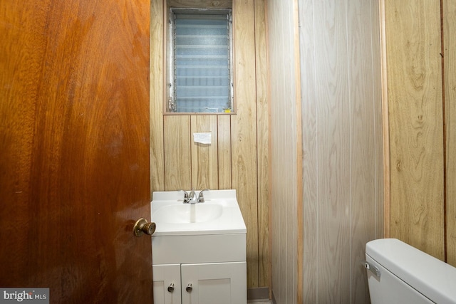 bathroom with wood walls, vanity, and toilet