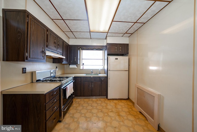 kitchen with under cabinet range hood, a sink, freestanding refrigerator, radiator, and range with gas cooktop