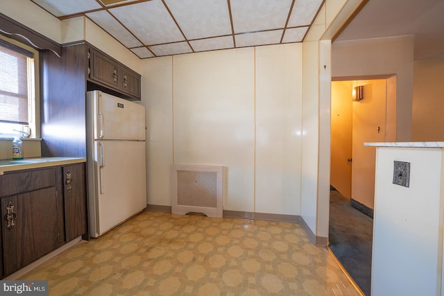 kitchen featuring freestanding refrigerator, visible vents, dark brown cabinetry, and light floors