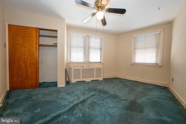 unfurnished bedroom featuring baseboards, radiator heating unit, ceiling fan, dark carpet, and a closet