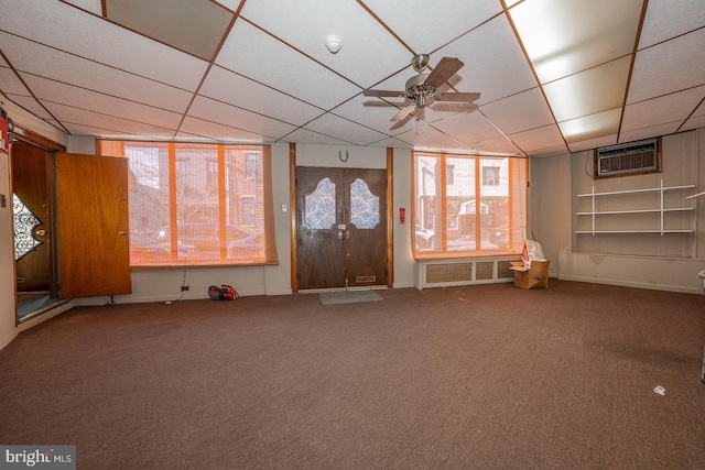 interior space featuring carpet floors, a wall unit AC, and a drop ceiling