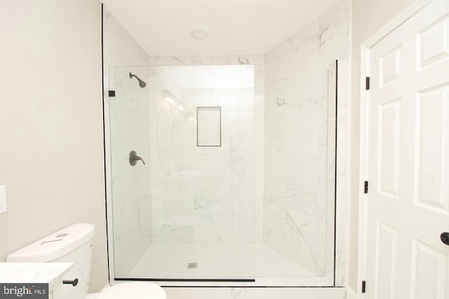 bathroom with toilet, vanity, and a shower with shower door