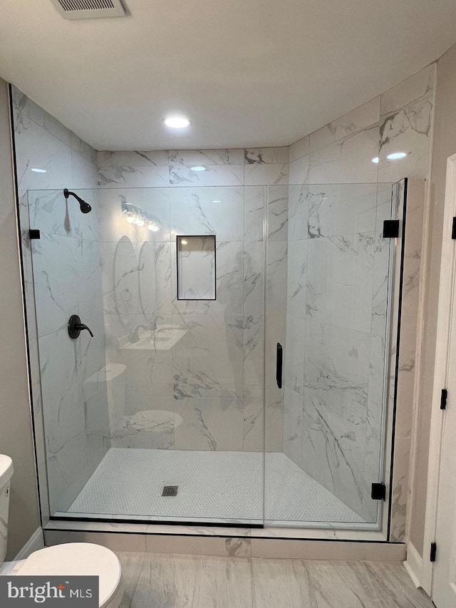 bathroom featuring a shower with shower door and toilet