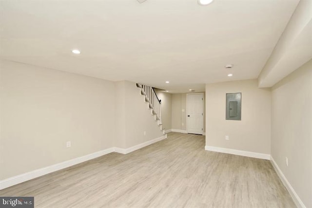 basement with electric panel and light hardwood / wood-style flooring