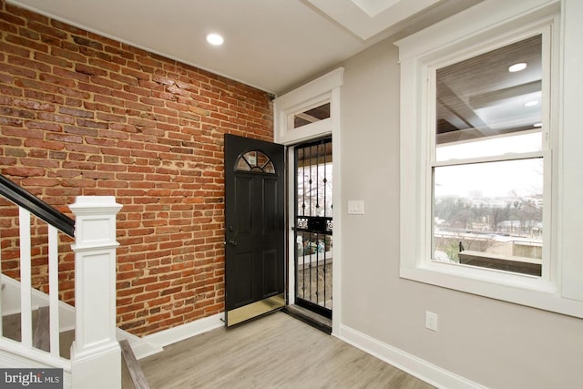 entrance foyer featuring brick wall and light hardwood / wood-style floors