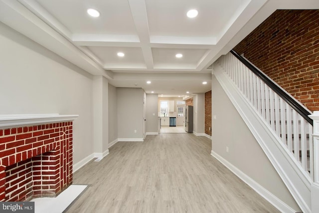 unfurnished living room with beamed ceiling, coffered ceiling, and light hardwood / wood-style floors