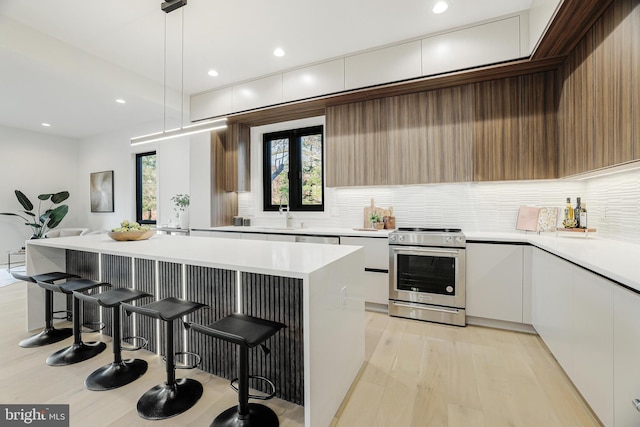 kitchen featuring stainless steel electric range, light hardwood / wood-style flooring, backsplash, white cabinets, and decorative light fixtures