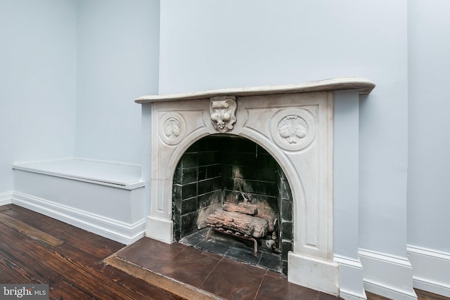 room details featuring a tile fireplace, baseboards, and wood finished floors