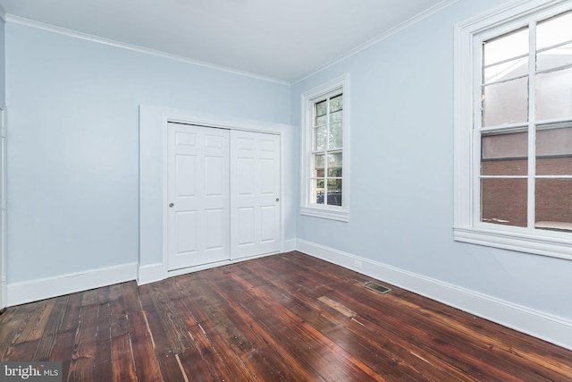 unfurnished bedroom featuring ornamental molding, dark wood-style flooring, a closet, and baseboards