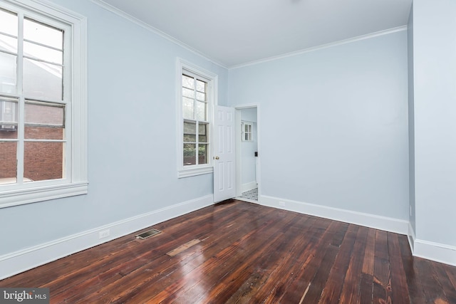 empty room with baseboards, visible vents, dark wood finished floors, and ornamental molding