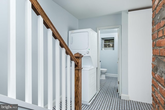 hall featuring stacked washer and dryer, stairway, and brick wall