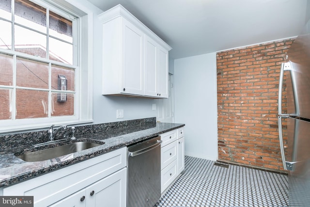 kitchen with dark stone countertops, white cabinetry, appliances with stainless steel finishes, and a sink