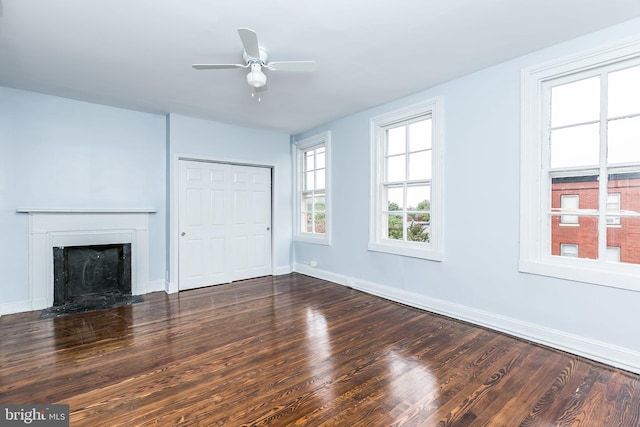 unfurnished living room with wood finished floors, a fireplace with flush hearth, a ceiling fan, and baseboards