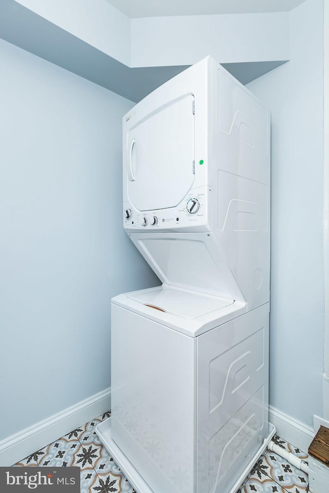 washroom with stacked washing maching and dryer, laundry area, and baseboards