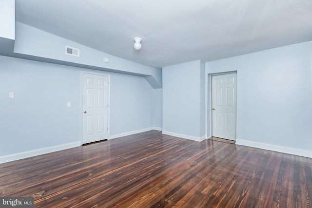 unfurnished room featuring baseboards, visible vents, and dark wood-style flooring