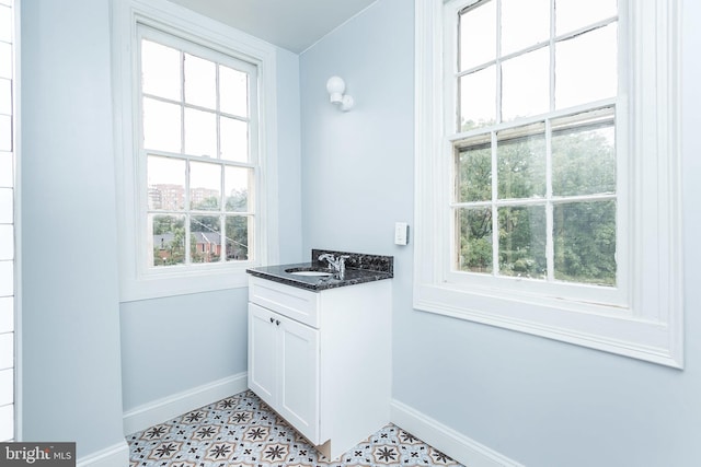 doorway to outside featuring a healthy amount of sunlight, light floors, baseboards, and a sink