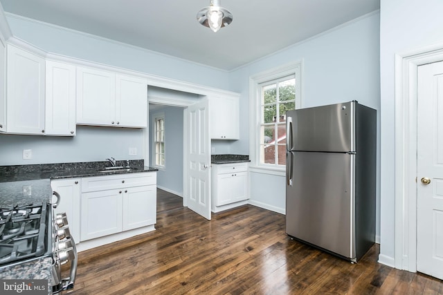 kitchen featuring dark wood-type flooring, white cabinets, ornamental molding, freestanding refrigerator, and gas stove