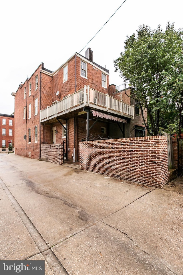 back of property featuring a chimney and brick siding